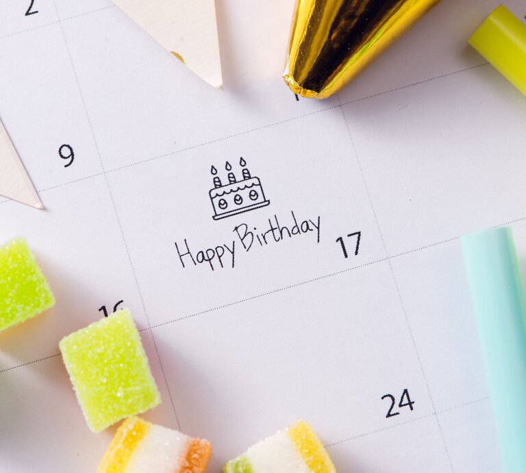 Ein Kalender mit der Markierung "Happy Birthday" am 17., umgeben von bunten Süßigkeiten, Partyhüten und Dekoration. | © Adobe Stock/makistock