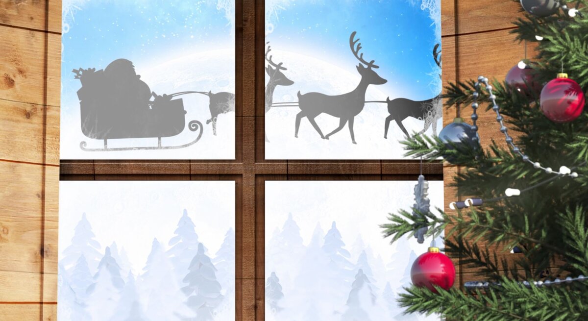 Ein Holzfenster mit einem weihnachtlichen Fensterbild, das eine winterliche Landschaft mit schneebedeckten Tannen und einem vorbeiziehendem Rentierschlitten zeigt.