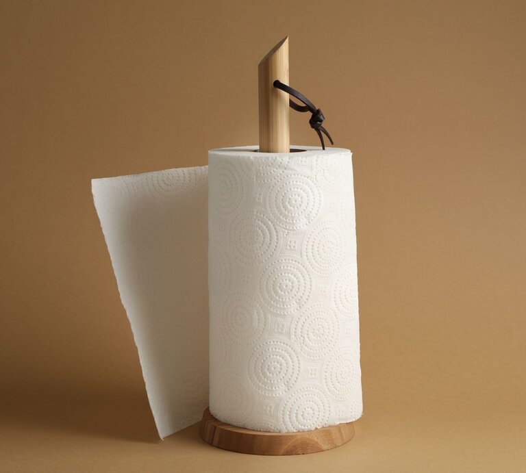 Selbst gebastelter Küchenrollenhalter aus hellem Holz mit strukturiertem Papier auf beigem Hintergrund, Blatt leicht abgerissen. | © AdobeStock/Liudmila Chernetska