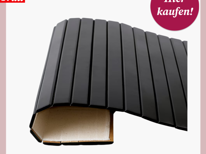 Schwarze, faltbare Schutzmatte aus Kunststoff mit gerillter Oberfläche liegt aufgerollt auf hellem Untergrund. | © Ikea 