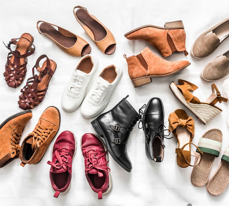Verschiedene Schuhe wie Sneaker, Sandalen, Boots und Hausschuhe in Braun-, Rot- und Beigetönen liegen kreisförmig auf weißem Untergrund. | © Adobe Stock/okkijan2010