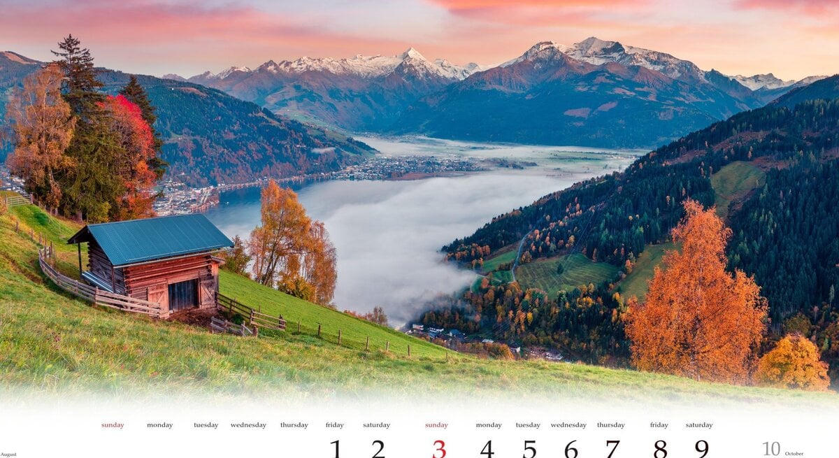 Ein Kalenderblatt, das eine kleine Holzhütte auf einer grünen Bergwiese zeigt, umgeben von Herbstbäumen, mit Blick auf einen nebelverhangenen See und schneebedeckte Berge im Morgenrot.