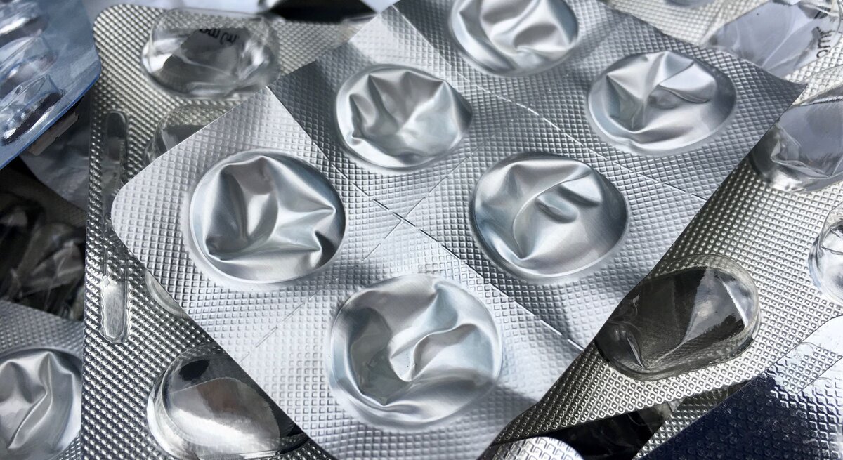 Mehrere leere, zusammengedrückte Blisterverpackungen liegen chaotisch übereinander auf einem hellen Untergrund.