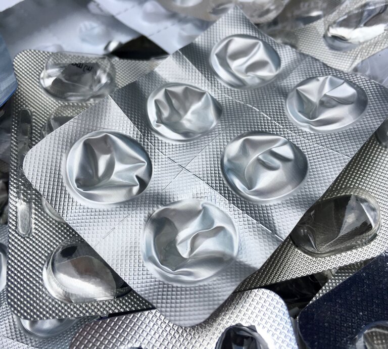 Mehrere leere, zusammengedrückte Blisterverpackungen liegen chaotisch übereinander auf einem hellen Untergrund. | © Adobe Stock/maerzkind