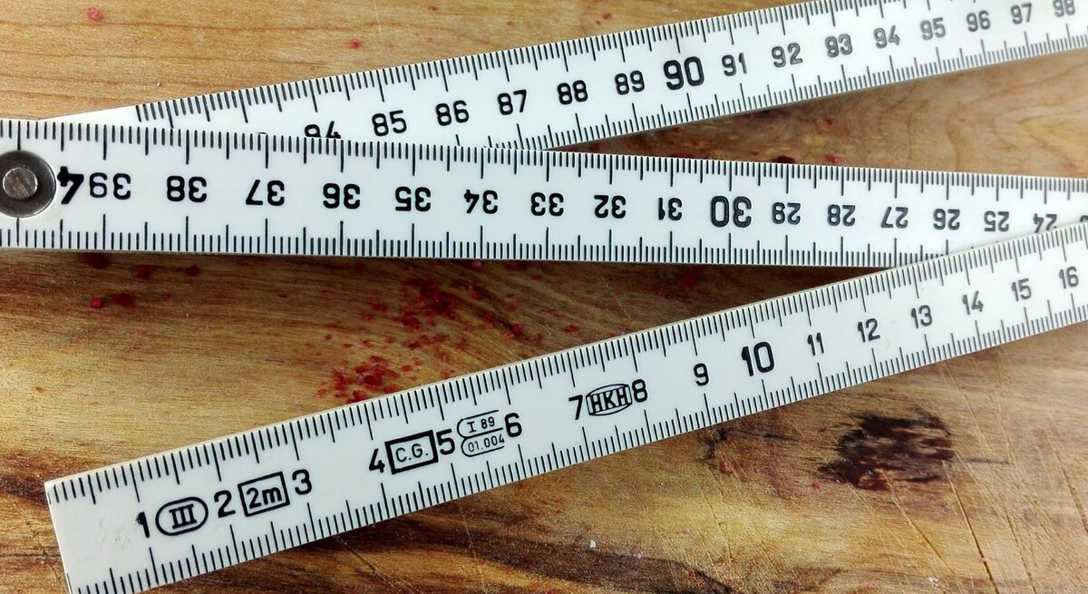Ein Zollstock mit Zentimeter-Skalierung liegt auf einem Holztisch.