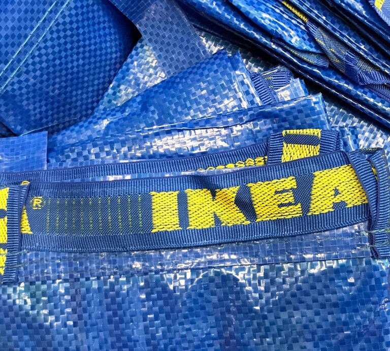 Blaue Einkaufstaschen aus Kunststoff mit gelbem "IKEA"-Logo liegen gestapelt aufeinander. | © Adobe Stock/Jarretera