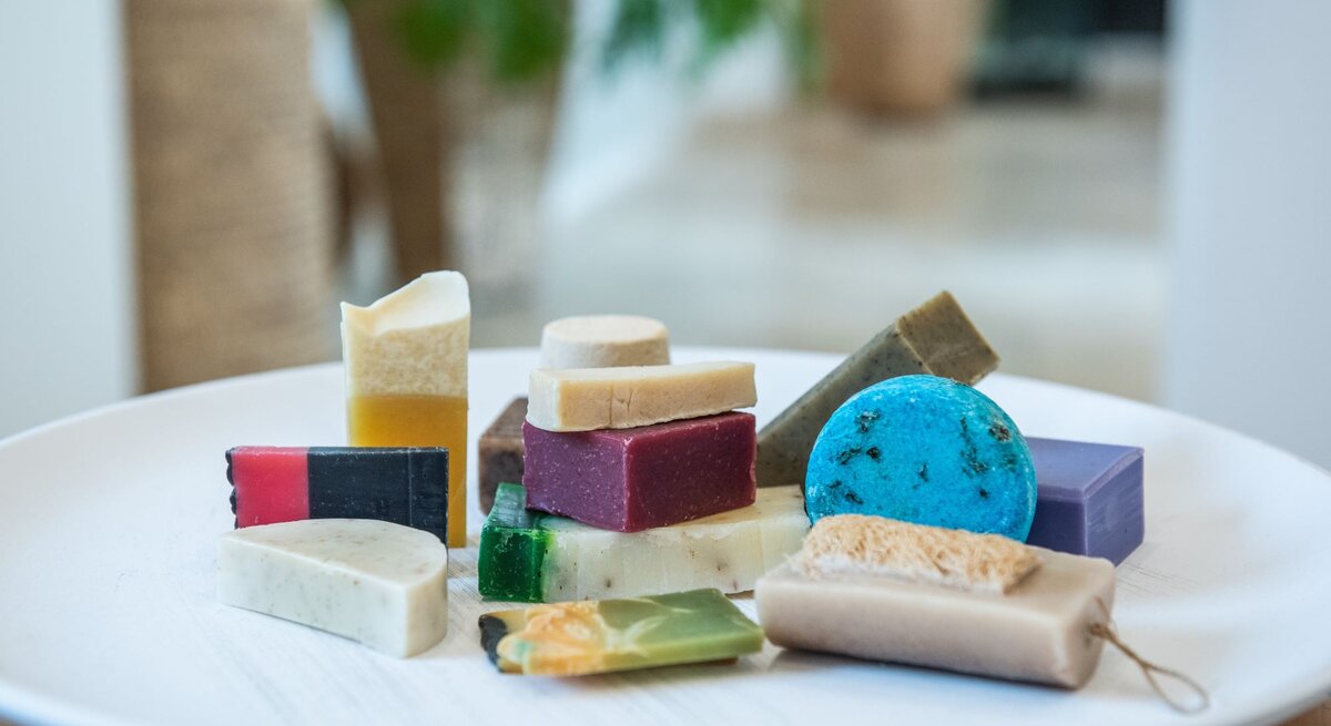 Bunt gemischte handgemachtes Shampoo in verschiedenen Formen und Farben liegen dekorativ auf einem weißen Keramikteller.