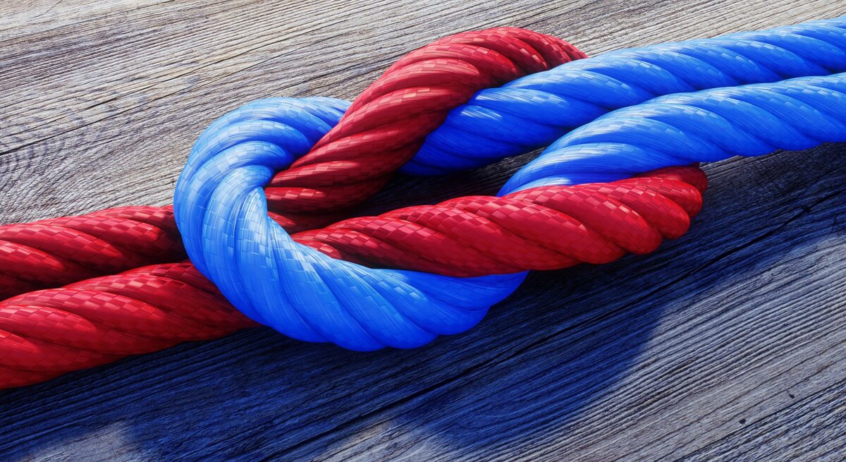 Rote und blaue Taue sind eng verknotet auf einem Holzboden.