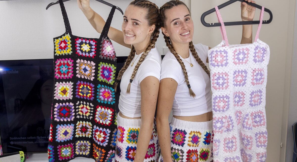 Die Lesotwins Leonie und Sophie zeigen selbst gehäkelte Röcke und Kleider und lachen dabei in die Kamera.