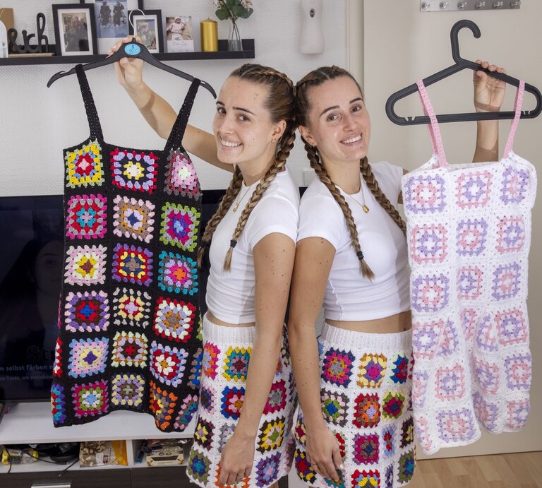 Die Lesotwins Leonie und Sophie zeigen selbst gehäkelte Röcke und Kleider und lachen dabei in die Kamera. | © Georg Lukas