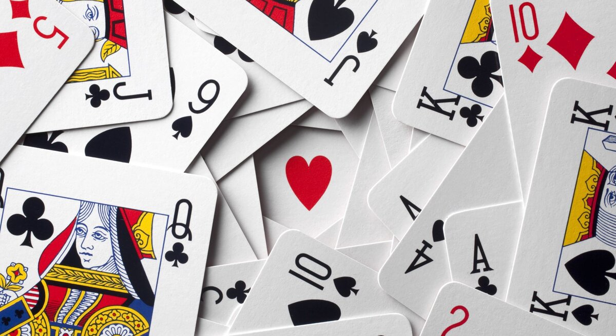 Ein Durcheinander von Spielkarten zeigt verschiedene Farben und Werte, mit einem roten Herz in der Mitte.