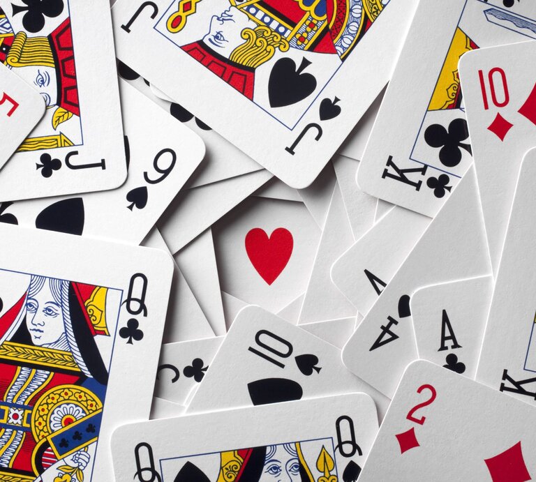 Ein Durcheinander von Spielkarten zeigt verschiedene Farben und Werte, mit einem roten Herz in der Mitte. | © Getty Images/malerapaso