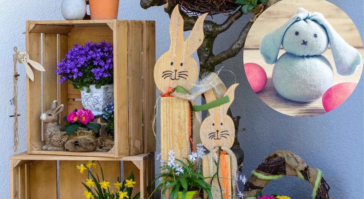 Liebevoll gestaltete Osterdekoration im Freien. Zu sehen sind Holzkisten, die als Regale dienen und mit frühlingshaften Pflanzen wie Primeln und Narzissen, sowie mit einem dekorativen Hasen gefüllt sind. 