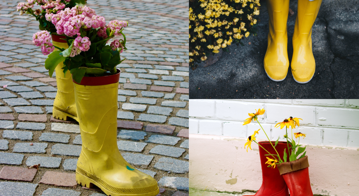 Zwei gelbe Gummistiefel mit pinken Blumen auf Pflastersteinen, daneben rote Stiefel mit Sonnenhutblüten vor heller Wand.