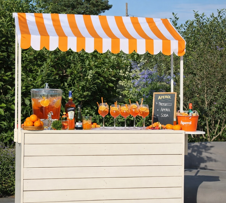 Ein mobiler Cocktailstand unter orangeweißer Markise zeigt gefüllte Aperolgläser, Spender mit Zitrusfrüchten und Deko Garten. | © Generiert mit KI (Erstellt mit ChatGPT) 