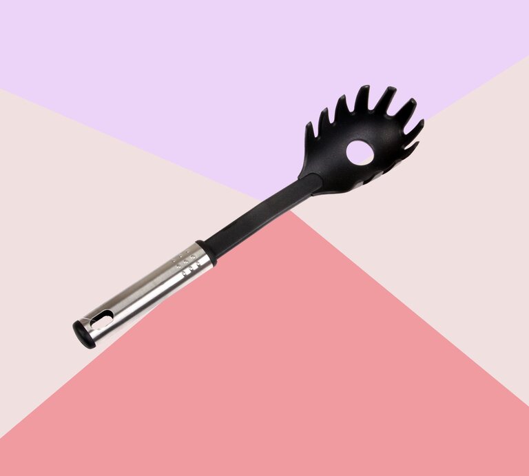 Schwarzer Spaghettilöffel mit Edelstahlgriff liegt schräg auf geometrischem Hintergrund in Rosa, Beige und Flieder. | © Canva/Collage: bildderfrau.de