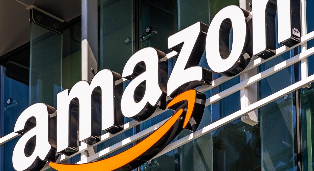 Nahaufnahme des bekannten Amazon-Schriftzugs mit orangem Pfeil auf Gebäudefront.