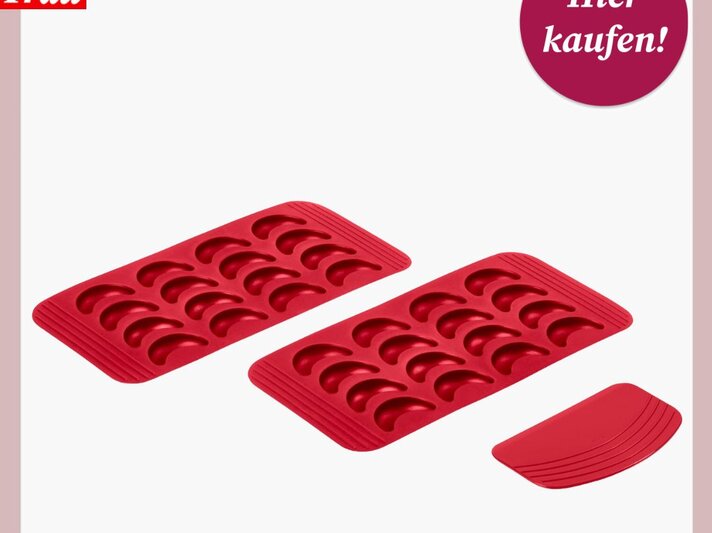 Zwei rote Silikonbackformen mit Halbmondmulden und ein passender Teigschaber für Vanillekipferl auf weißem Untergrund. | © Tchibo