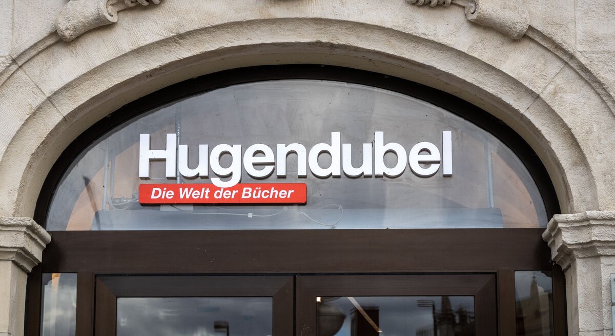 Eingang eines Hugendubel-Buchladens mit Schriftzug 'Die Welt der Bücher' unter einem steinernen Torbogen.