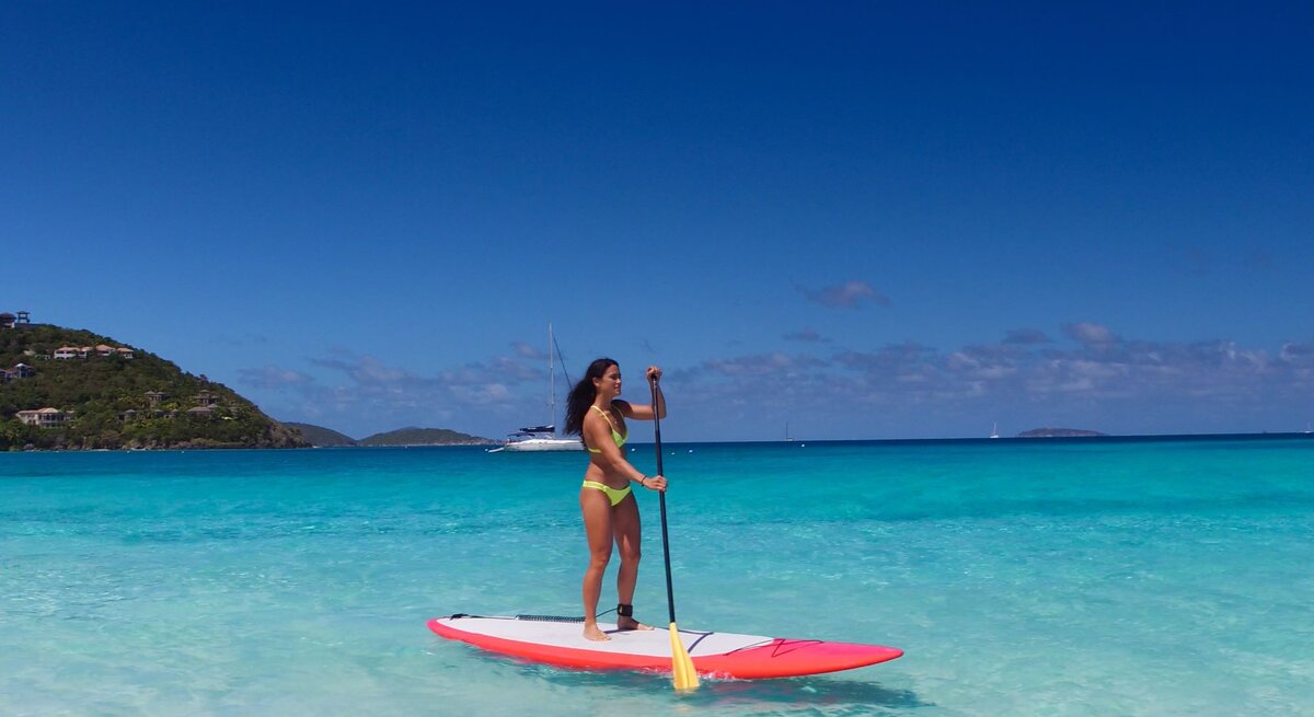 Eine Frau paddelt in der Karibik auf einem SUP, Stand Up Paddle Board.