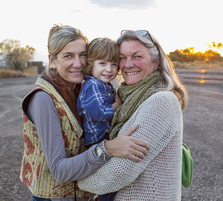 Oma, Mutter und Sohn halten sich im Arm und gucken den Betrachter an. | © gettyimages/	Marc Romanelli