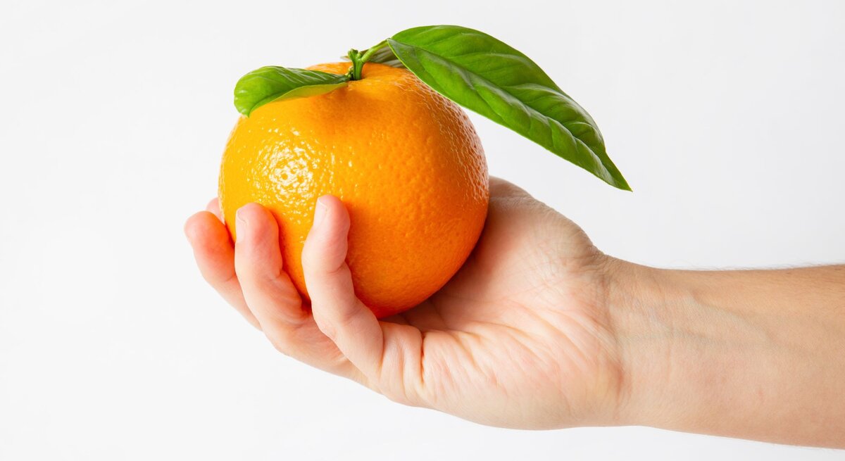 Jemand hält eine Orange in der Hand.