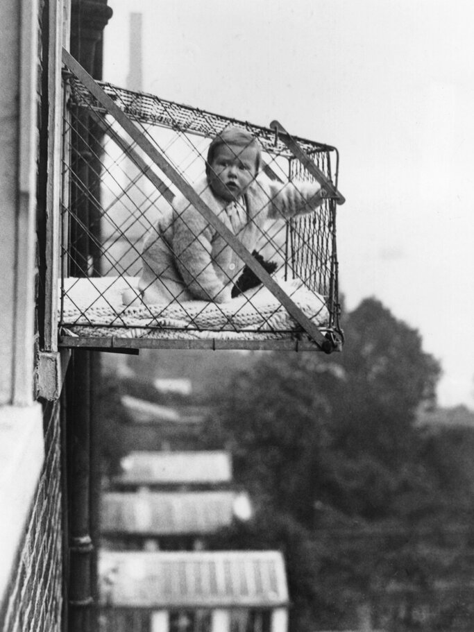Baby in einem Käfig am Fenster zur damaligen Zeit. | © Getty Images/Fox Photos