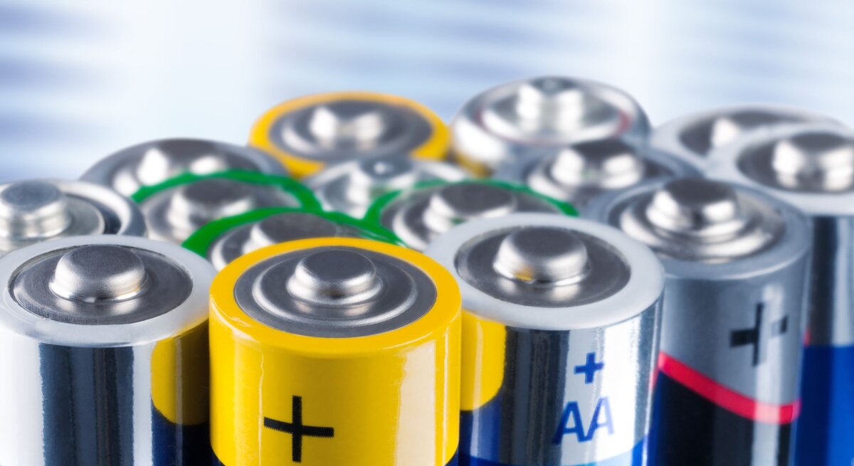 Nahaufnahme mehrerer AA-Batterien in verschiedenen Farben und Marken, aufrecht stehend vor verschwommenem Hintergrund.