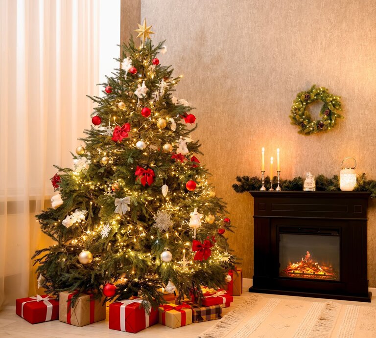 Geschmückter Weihnachtsbaum mit roten Schleifen und glänzenden Kugeln, daneben leuchtender Kamin mit Kerzen und Tannendekor. | © Shutterstock/New Africa