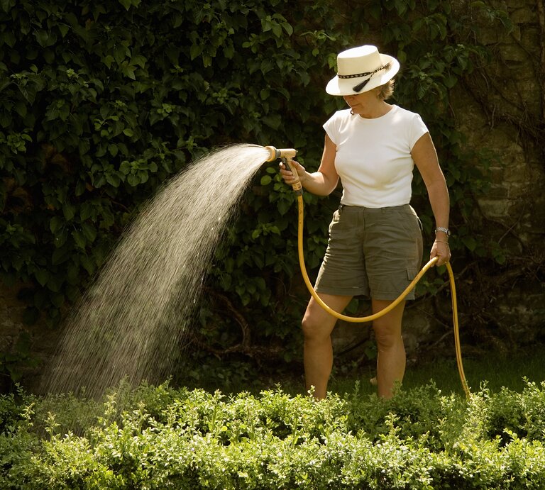 Frau wässert ihren Garten | © GettyImages/	Michael Dunning