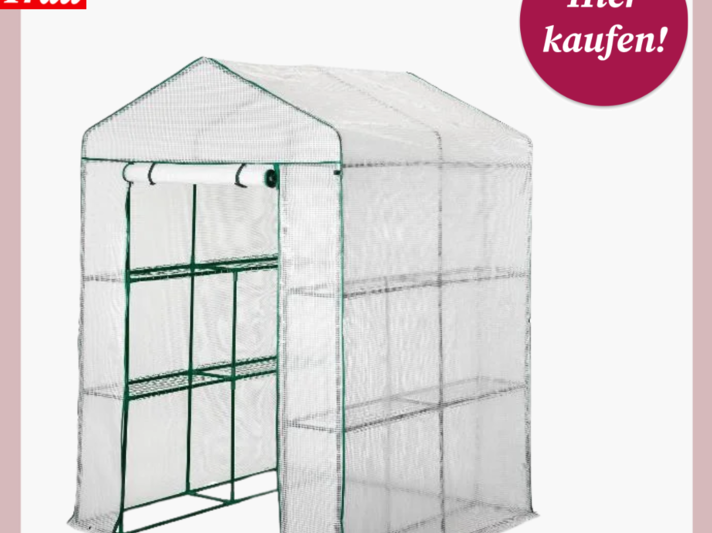 Kompaktes Gewächshaus mit grünem Metallgestell und durchsichtiger Kunststoffabdeckung, vorn mit aufrollbarer Tür und Regalflächen innen. | © Lidl 