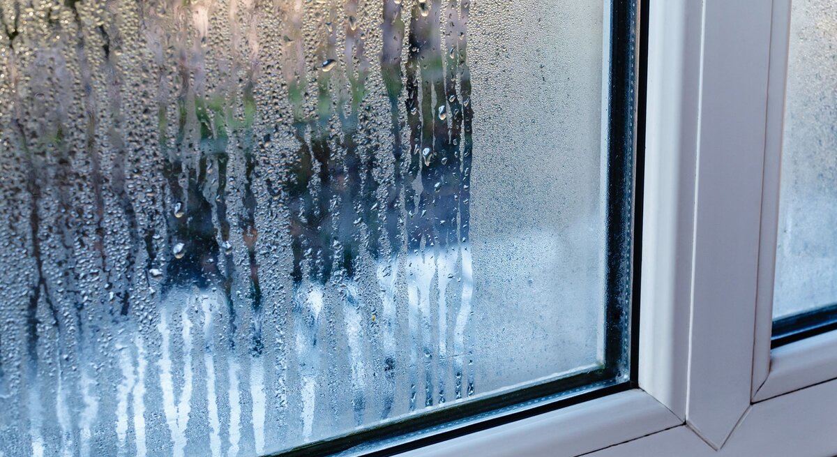Kondenswasser läuft an einer beschlagenen Fensterscheibe herab.