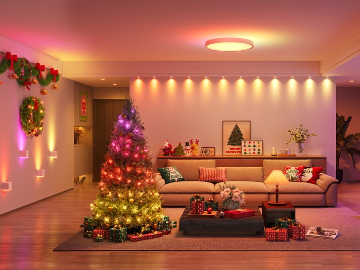 Ein festlich geschmückter Weihnachtsbaum mit bunten Lichtern steht in einem warm beleuchteten Wohnzimmer voller Geschenke und Dekorationen. | © Govee
