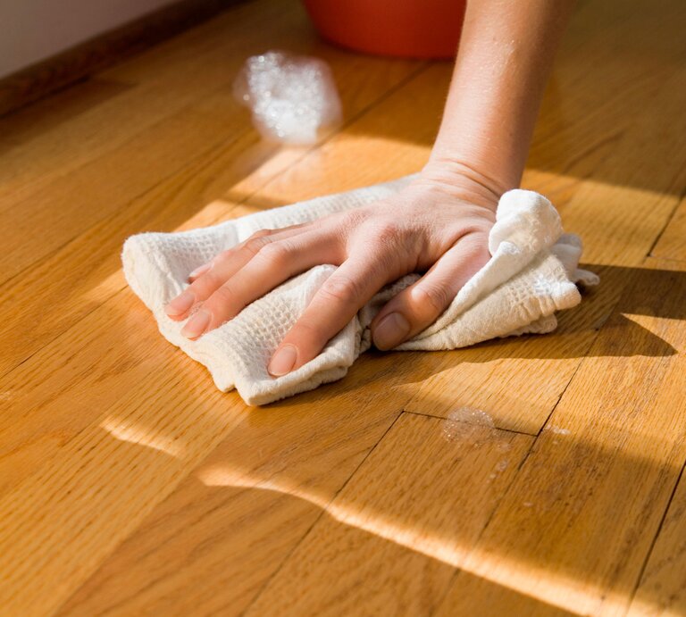Hand mit Lappen beim Parkett reinigen | © Getty Images