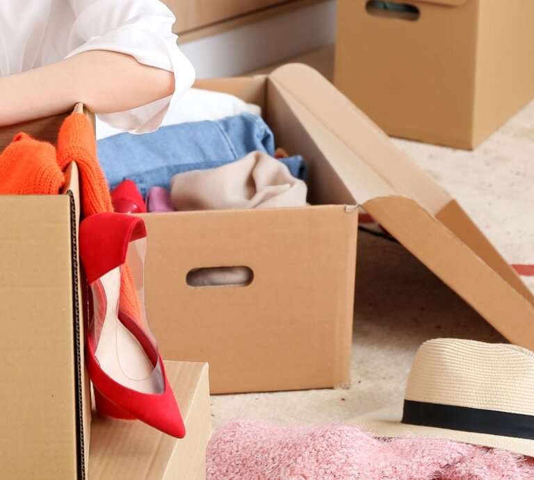 Eine junge Frau sitzt überfordert zwischen mehreren vollgestopften Kartons. | © Shutterstock/Pixel-Shot