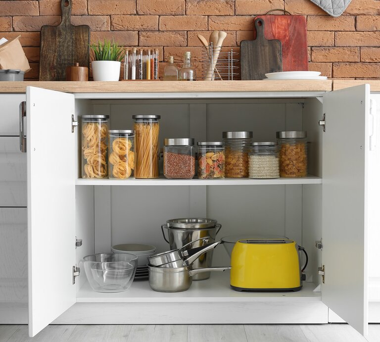 Geöffneter Küchenschrank mit gefüllten Schraubgläsern und einem gelben Toaster darin. | © Adobe Stock/Pixel-Shot