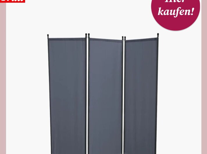  Das Bild zeigt einen dreiteiligen Paravent als Sichtschutz für den Balkon, gefertigt aus dunkelgrauem Stoff, der zwischen schlanken, vertikalen Metallstangen gespannt ist. Dieses Stellwand-System scheint flexibel positionierbar zu sein, um Privatsphäre zu schaffen. Oben im Bild befindet sich das Logo „Bild der Frau“ und ein magentafarbener Kreis mit der Aufschrift „Hier kaufen!“, was darauf hinweist, dass der Paravent zum Verkauf steht und wahrscheinlich über einen angegebenen Link oder in einem Online-Shop erworben werden kann. Der Hintergrund ist in einem sanften Rosa gehalten, das den dunklen Sichtschutz gut zur Geltung bringt. | © Lidl