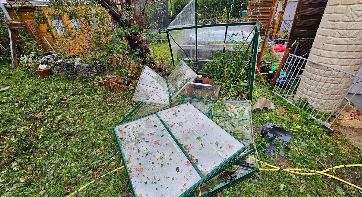 Zerstörter Garten mit zertrümmertem Gewächshaus nach Unwetter