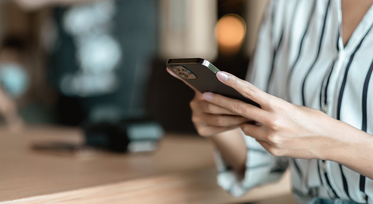 Frau hält ein Handy in der Hand und tippt. 