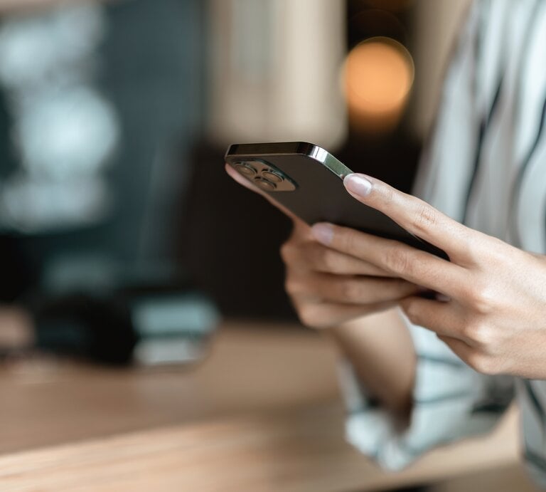 Frau hält ein Handy in der Hand und tippt.  | © Adobe Stock