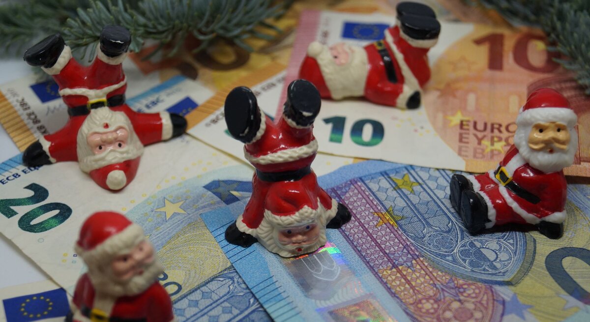 Zu sehen sind Weihnachtsmänner, die auf Geld tanzen