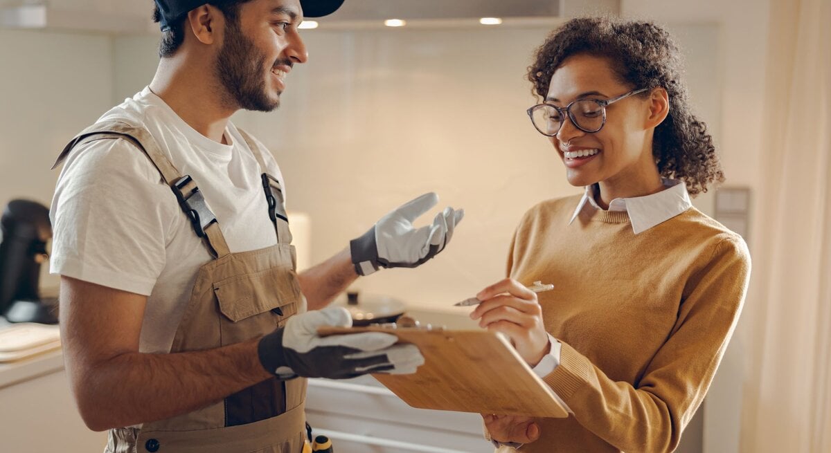 Zu sehen ist eine Frau, die sich mit einem Handwerker unterhält