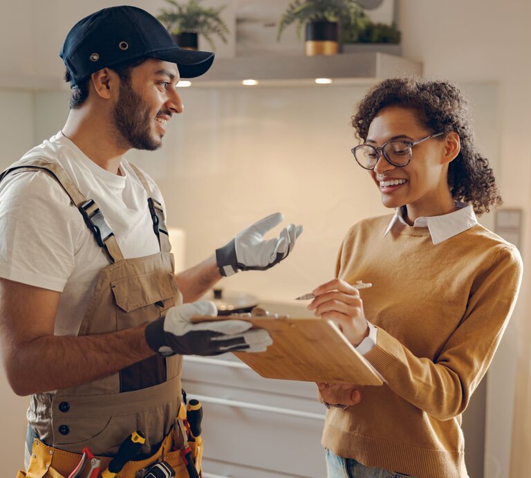 Zu sehen ist eine Frau, die sich mit einem Handwerker unterhält | © GettyImages/Voronchuk Daria