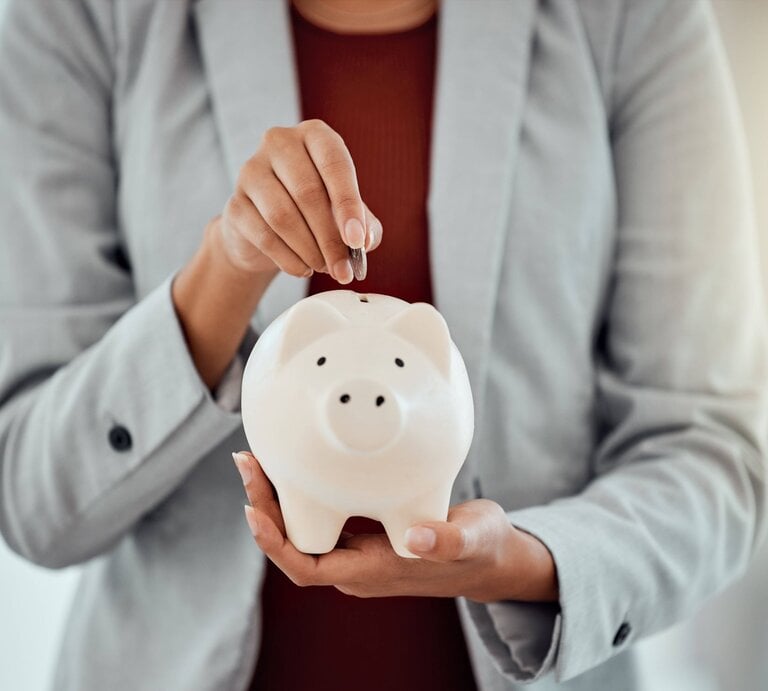 Eine Frau packt Geld in ein Sparschwein. | © IMAGO/Zoonar