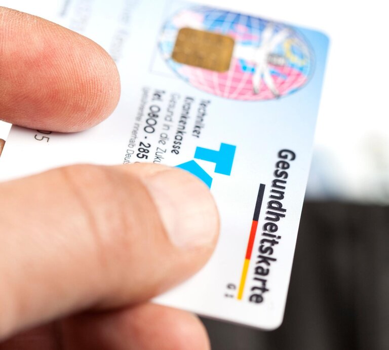 Person gibt eine Krankenkarte der Techniker Krankenversicherung einem Arzt.  | © Getty Images