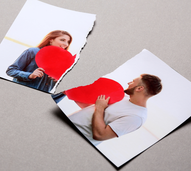 Zerrissenes Foto auf grauem Untergrund zeigt zwei Personen, jeweils mit einem roten Herz vor sich, getrennt durch einen Riss. | © Canva