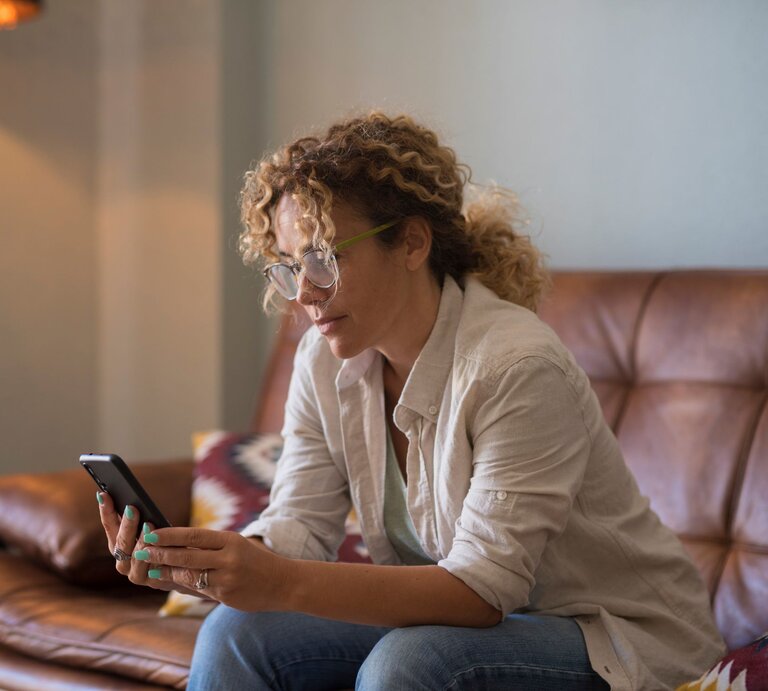 Frau auf Sofa mit Handy | © Adobe Stock / simona