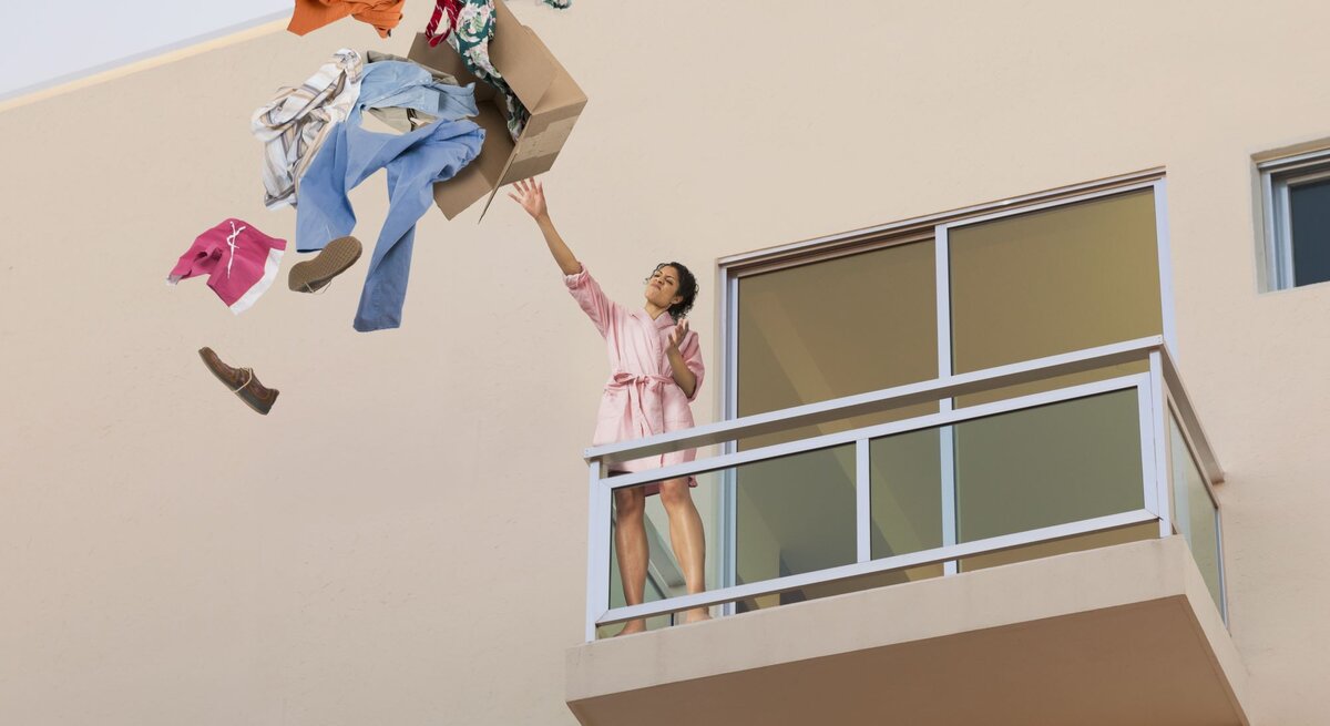 Eine Frau wirft einen Karton mit den Habseligkeiten ihres Ex-Freundes vom Balkon.