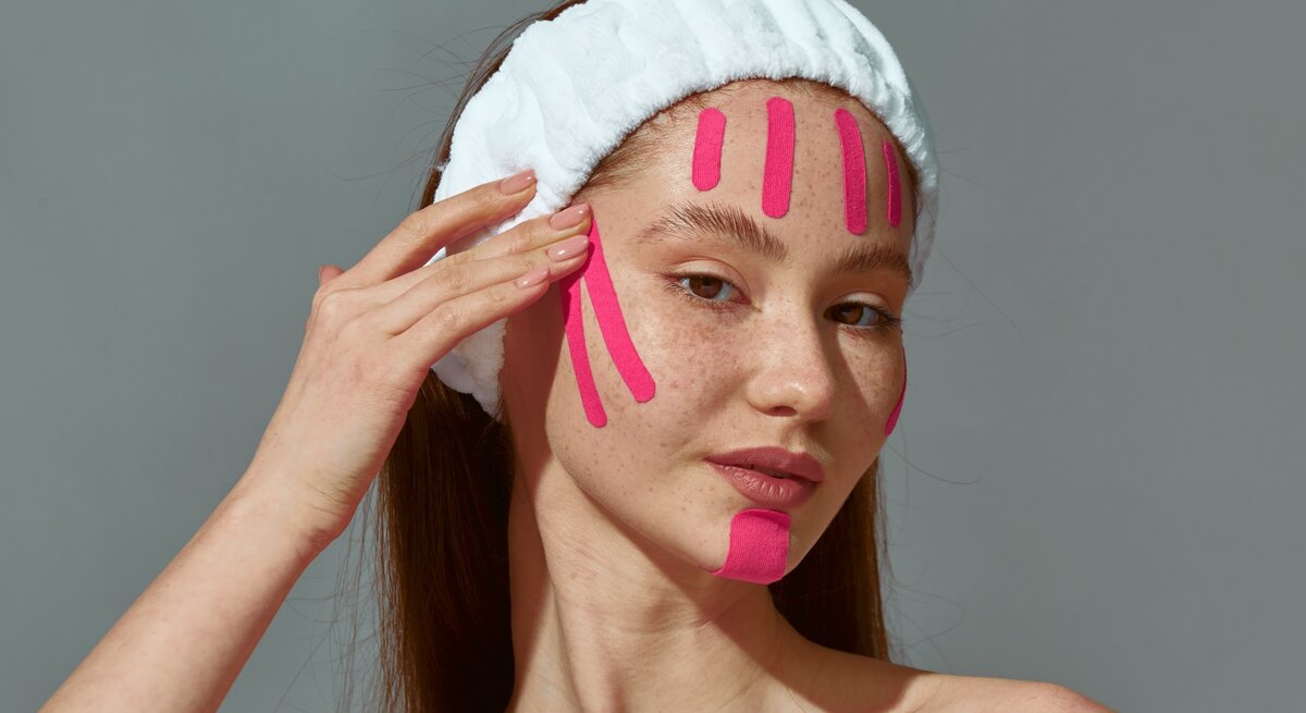 Zu sehen ist eine junge Frau mit rosafarbenen Facetaping