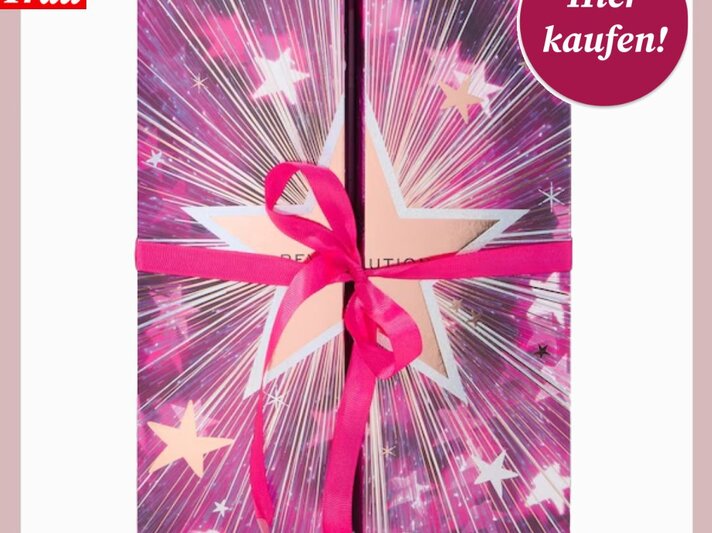 Quadratischer Adventskalender in lebhaften pinken und violetten Farben mit goldenen Akzenten und Sternen, verziert von einer hübschen Satinschleife. | © Collage: Douglas/ BILD der FRAU
